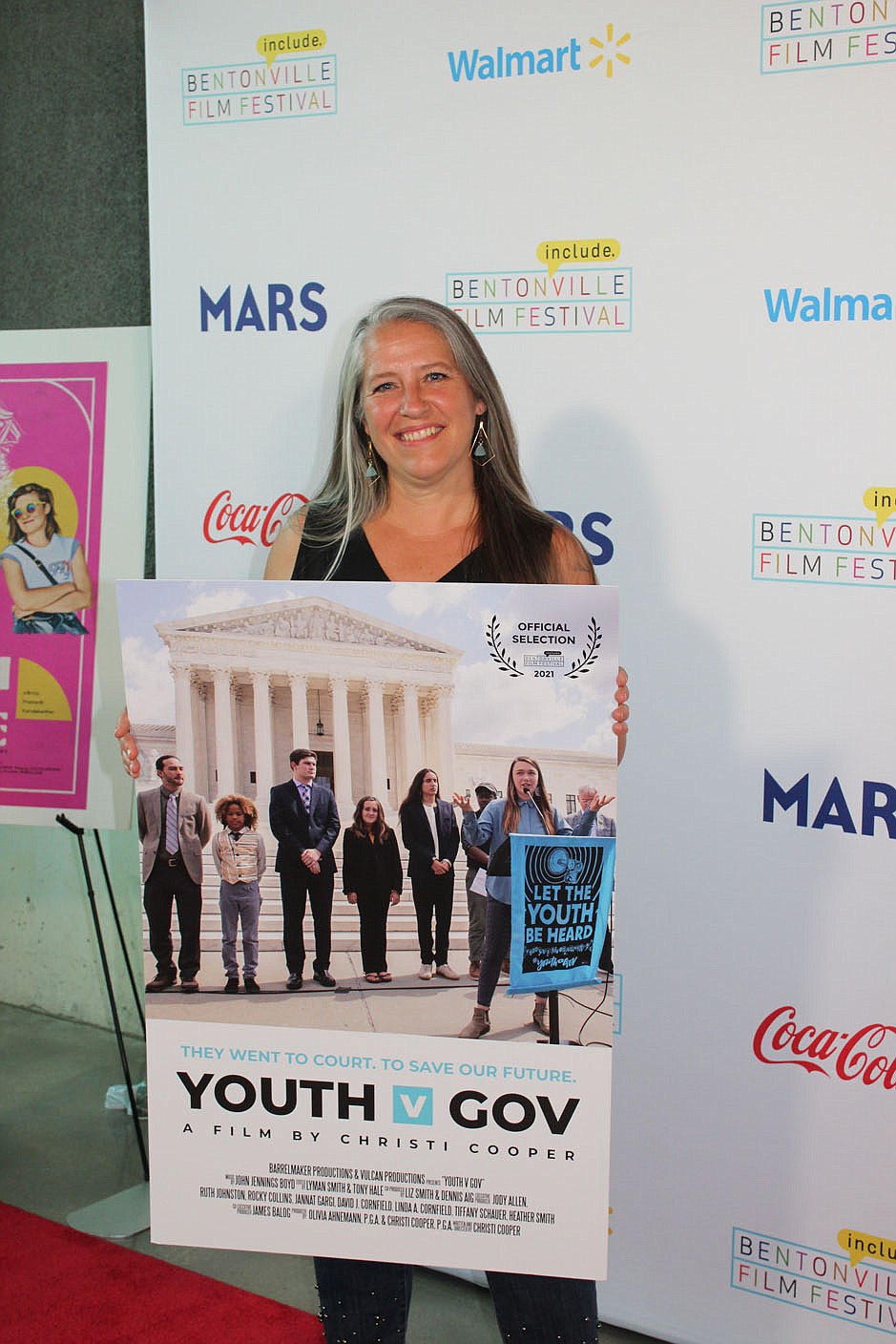 Writer, director and producer Christi Cooper stands with a poster of her Bentonville Film Festival entry, "Youth V Gov."
(NWA Democrat-Gazette/Carin Schoppmeyer)