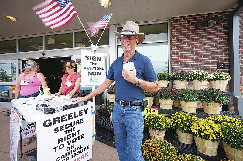 In this Friday, July 23, 2021, photograph, John G. Gauthiere, president of his own civil engineering consulting firm, collects signatures outside a grocery store in west Greeley, Colo.  Figures released this month show that population growth continues unabated in the South and West, even as temperatures rise and droughts become more common. That in turn has set off a scramble of growing intensity in places like Greeley to find water for the current population, let alone those expected to arrive in coming years. (AP Photo/David Zalubowski)