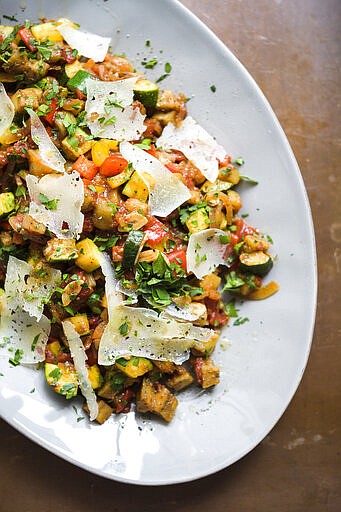 This image released by Milk Street shows a recipe for Spanish ratatouille, a combination of saut&#xe9;ed summer vegetables with shaved curls of manchego cheese. (Milk Street via AP)