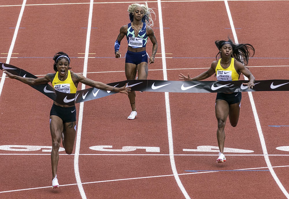 Jamaica's Elaine Thompson-Herah, left, wins the 100 meters, as American track and field sprinter Sha'carri Richardson, center, also competes, Saturday, Aug. 21, 2021, at the Prefontaine Classic track and field meet in Eugene, Ore. Richardson finished in last place. (AP Photo/Thomas Boyd)