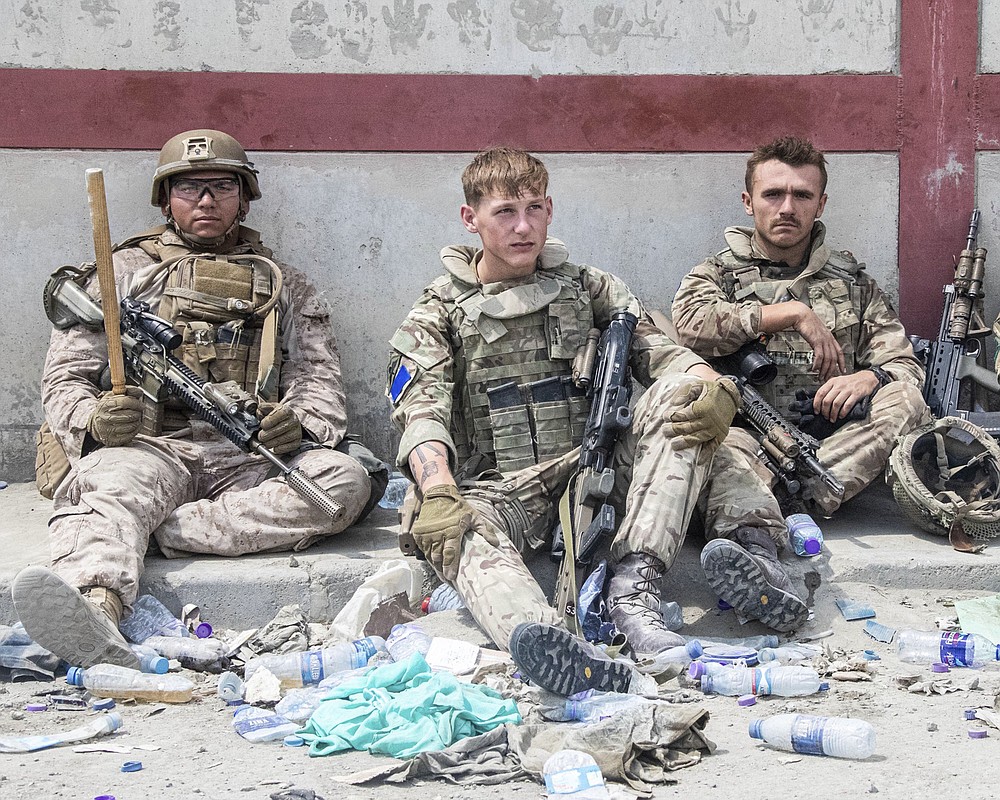 In this photo provided by the Ministry of Defence, members of the British and US, left) military engaged in the evacuation of people out of Kabul, Afghanistan take a brief rest from their duties on Friday, Aug. 20, 2021. (Ministry of Defence via AP)