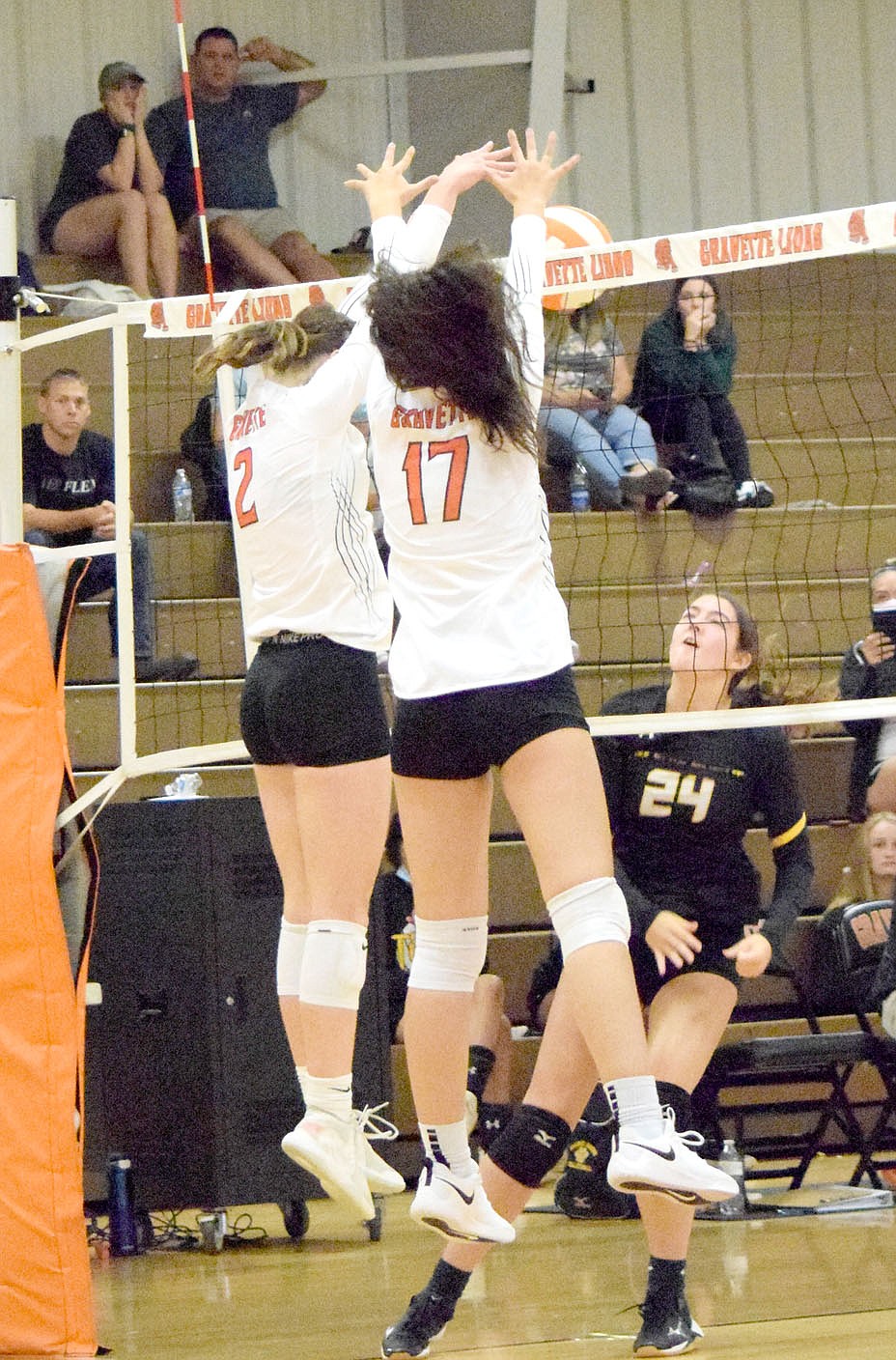 Westside Eagle Observer/MIKE ECKELS
Working together, Lady Lion Abby Smith (2) and Ella Pinches (17) deflect the ball back over the net into Lady Tiger territory during the second set of the Gravette-Prairie Grove varsity match at the Competition Gym in Gravette Thursday night. The Lady Lions took its second win of the 2021 season in three straight sets over the Lady Tigers.