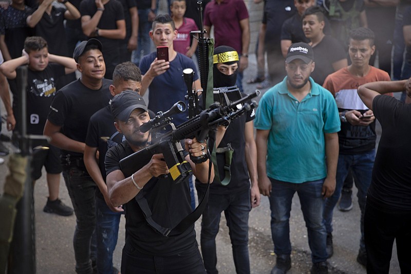 A Palestinian gunman fires his weapons in the air during the funeral of Imad Hashash, 15, who was killed in clashes with Israeli security forces on early Tuesday morning, during a raid in the Balata refugee camp, in the West Bank city of Nablus, Tuesday, Aug. 24, 2021. Palestinian authorities said Hashash died after being shot in the head during clashes with soldiers in the northern city of Nablus. The Israeli military said soldiers were carrying out an arrest raid in the Balata refugee camp when they came under attack from nearby rooftops by Palestinians who fired guns and threw large stone blocks. (AP Photo/Majdi Mohammed)
