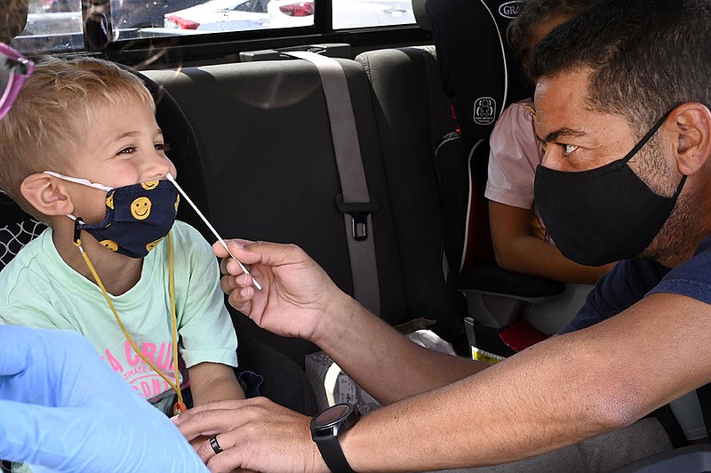 Mark Barsoun helps his son Jordan Barsous, 4, with the swab for a rapid COVID-19 test at Palos Verdes High School in Palos Verdes Estates, Calif., on Tuesday, Aug. 24, 2021. Barsoun will be attending St. Peters school. The district is encouraging all students and staff to test before the first day of school, August 25, and there are three sites for the drive-up testing. (Brittany Murray/The Orange County Register/SCNG via AP)