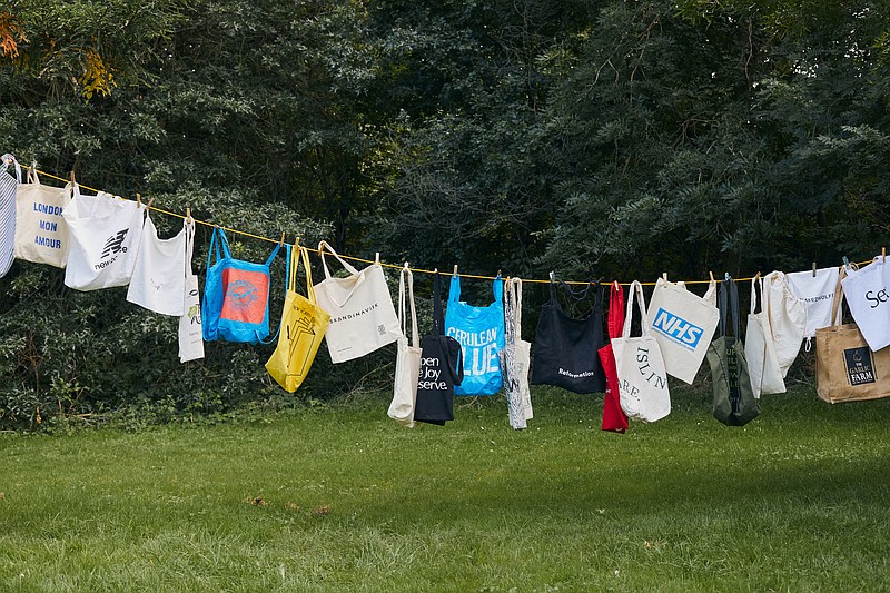 A laundry line of cotton totes accumulated by a single person in London, Aug. 16, 2021. An organic cotton tote needs to be used 20,000 times to offset its overall impact of production, according to a 2018 study by the Ministry of Environment and Food of Denmark. (The New York Times/Suzie Howell)