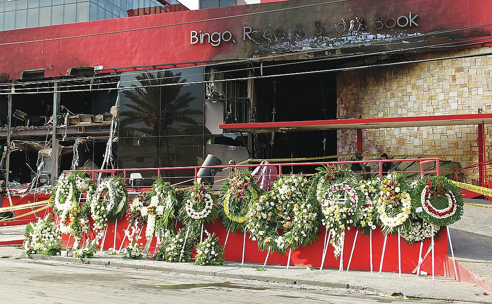 FILE - In this Aug, 27, 2011, file photo, a makeshift memorial of funeral wreaths line the circular driveway of the Casino Royale in Monterrey, Mexico. A surveillance tape showed eight or nine men arriving in four cars Thursday at the gambling house and setting fire to the building; trapping dozens of people inside and killing at least 52 people, mostly women. (AP Photo/Hans-Maximo Musielik, File)