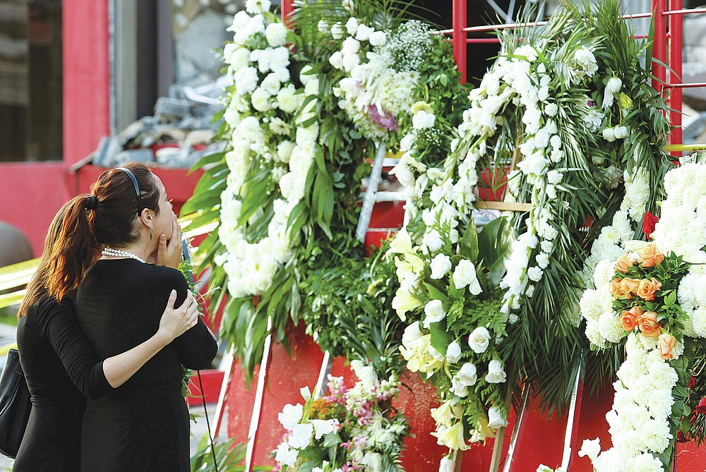 Family members of a victim of the Casino Royale's deadly arson attack stand at a makeshift memorial, in front of the charred gambling house in Monterrey, Mexico, Saturday Aug, 27, 2011. A surveillance tape showed eight or nine men arriving in four cars Thursday at the casino and setting fire to the building; trapping dozens of people inside and killing at least 52 people, mostly women. (AP Photo/Hans-Maximo Musielik)