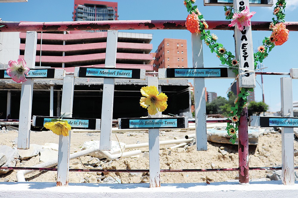 In front of the land occupied by the Casino Royale, relatives have installed a memorial to remember the victims of the Aug. 25, 2011 attack on the Casino Royale, in Monterrey, Mexico, Friday, Aug. 20, 2021. The dozens of white crosses bear the names of the deceased. (AP Photo/Marcos Martinez Chacon)