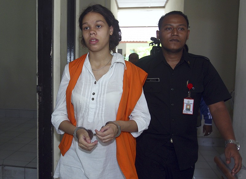 FILE - In this April 7, 2015 file photo, handcuffed Heather Mack of Chicago, Ill. is escorted by an Indonesian prison guard to a court room for her trial at Denpasar District Court in Bali, Indonesia. Mack, serving a 10-year sentence for assisting her then-boyfriend in her mother's murder and stuffing the body in a suitcase on Indonesia's tourist island of Bali in 2014 will be released from prison in October after completing her sentence, an Indonesian lawyer said Thursday, Aug. 26, 2021. (AP Photo/Firdia Lisnawati File)