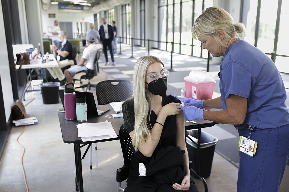 Nurse Velvet Shoults (right) administers a covid-19 vaccine booster to Payton Dougherty (center), Friday, August 27, 2021 at the J.B. Hunt headquarters in Lowell. Miss Arkansas USA Stephanie Barber appeared at a vaccine clinic hosted by the Northwest Arkansas Council to encourage vaccinations and take photos with participants. Check out nwaonline.com/210828Daily/ for today's photo gallery.
(NWA Democrat-Gazette/Charlie Kaijo)