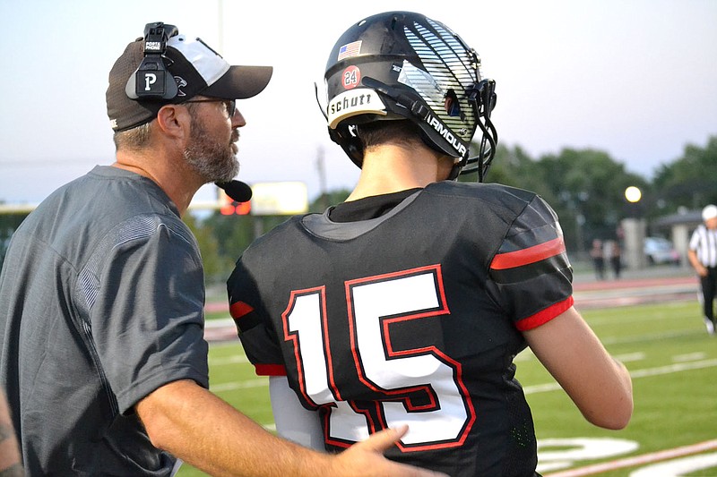 Assistant coach Jacob Meyers talks with quarterback Gavin Dixon on the sidelines Friday, Aug. 27, during the home game against Shiloh.