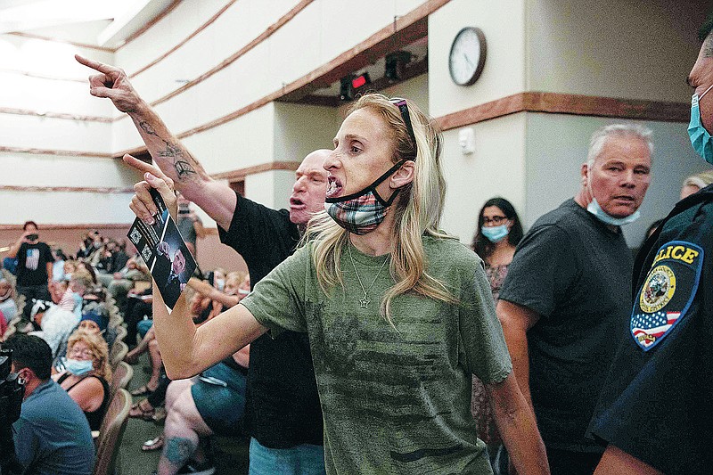 FILE - In this Aug. 12, 2021, file photo, protesters against a COVID-19 mandate gesture as they are escorted out of the Clark County School Board meeting at the Clark County Government Center, in Las Vegas. A growing number of school board members across the U.S. are resigning or questioning their willingness to serve as meetings have devolved into shouting contests over contentious issues including masks in schools. (Bizuayehu Tesfaye/Las Vegas Review-Journal via AP, File)