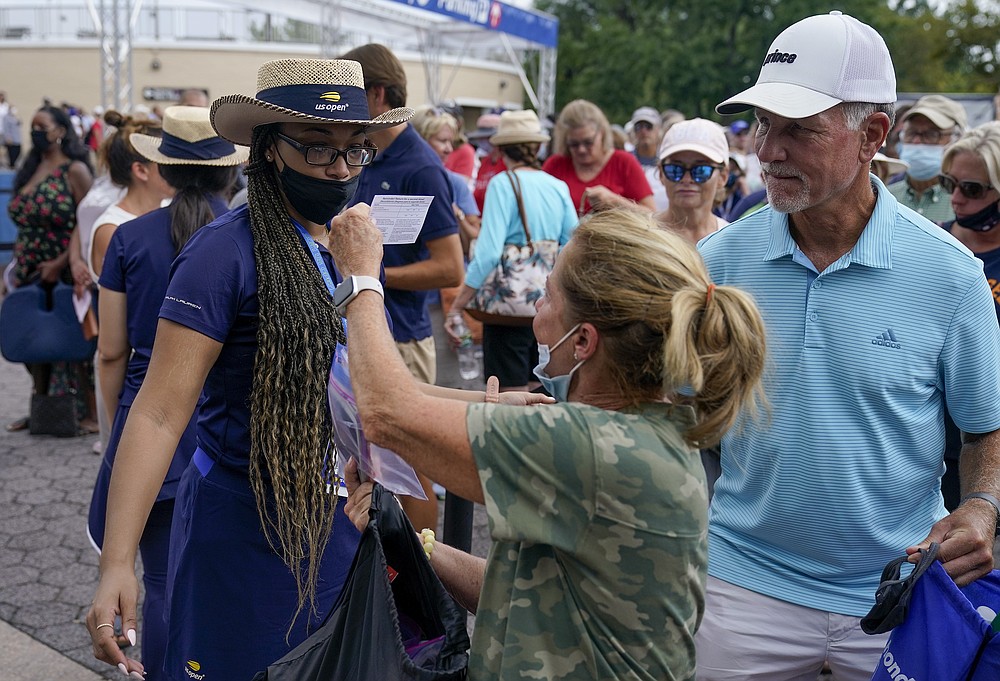 Tenisa fani, pirmdien, 2021. gada 30. augustā, Ņujorkā, uzrāda savu apliecinājumu par vakcinācijas biļetēm, lai ieietu ASV atklātā tenisa turnīra pirmajā kārtā.  (AP fotoattēls / Seth Wenig)