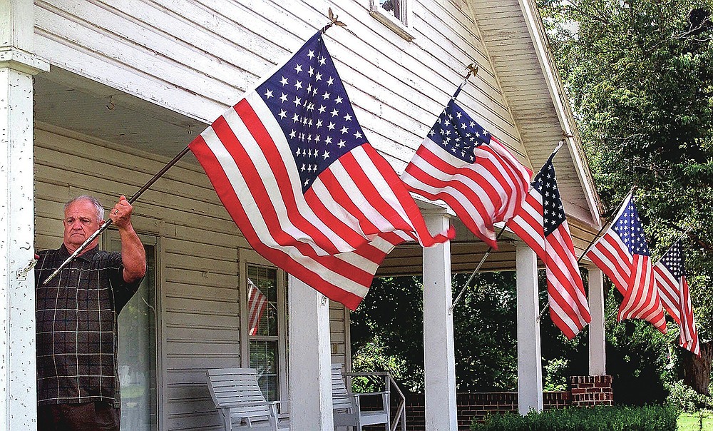ADVANCE FOR PUBLICATION ON FRIDAY, SEPT. 10, AND THEREAFTER - FILE - In this Thursday, Sept. 13, 2001 file photo, Liberty County resident Rev. M. Timonthy Elder, Sr., retired, repositions one of his wind-blown U.S. flags in Bristol, Fla. Rev. Elder displayed the flags as a show of his family's support for America following terrorist attacks in New York City and Washington two days earlier. (AP Photo/Phil Coale, File)