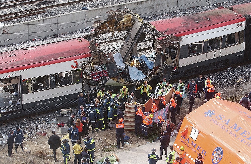 ADVANCE FOR PUBLICATION ON FRIDAY, SEPT. 10, AND THEREAFTER - FILE - In this March 11, 2004 file photo, rescue workers cover bodies alongside a bomb-damaged passenger train, following a number of explosions in Madrid, Spain, which killed more than 170 rush-hour commuters and wounded more than 500 in Spain's worst terrorist attack ever. An Al-Qaida-linked group that claimed responsibility for the Madrid train bombings warned European nations that they have only two weeks to withdraw troops from Iraq or face the consequences, a pan-Arab newspaper reported Friday, July 2, 2004. (AP Photo/Paul White, File)