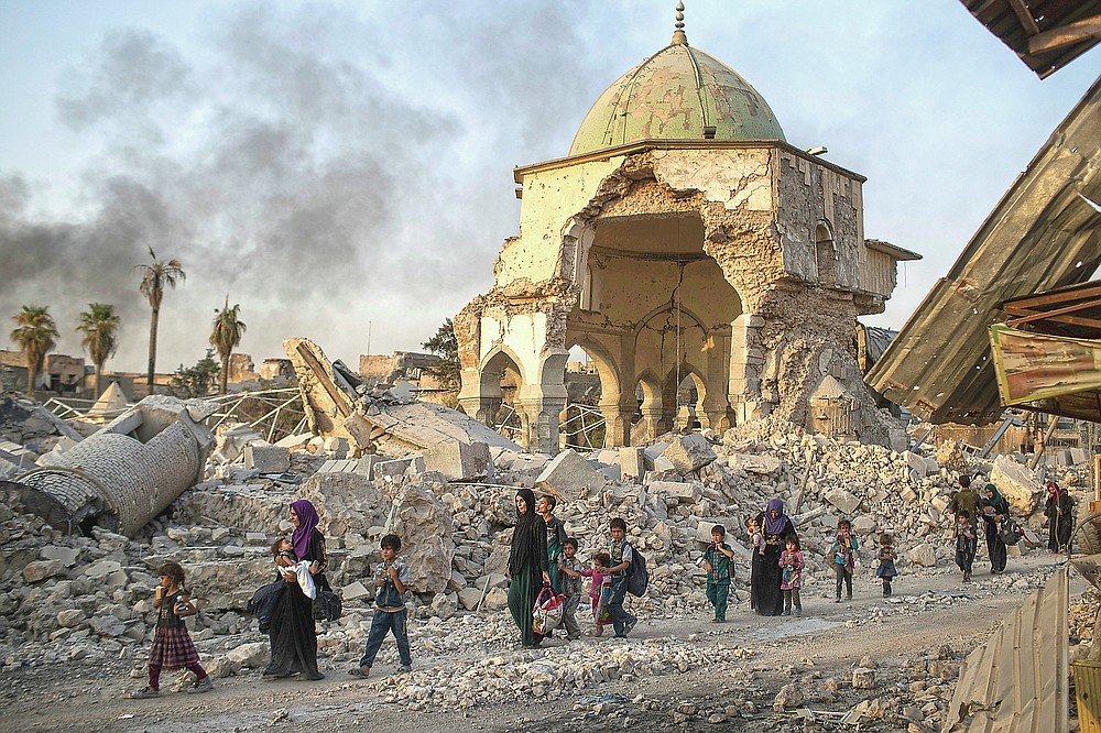 ADVANCE FOR PUBLICATION ON FRIDAY, SEPT. 10, AND THEREAFTER - FILE - In this Tuesday, July 4, 2017 file photo, fleeing Iraqi civilians walk past the heavily damaged al-Nuri mosque as Iraqi forces continue their advance against Islamic State militants in the Old City of Mosul, Iraq. As Iraqi forces continued to advance on the last few hundred square kilometers of Mosul held by the Islamic State group, the country's Prime Minister said Tuesday the gains show Iraqis reject terrorism. (AP Photo/Felipe Dana, File)