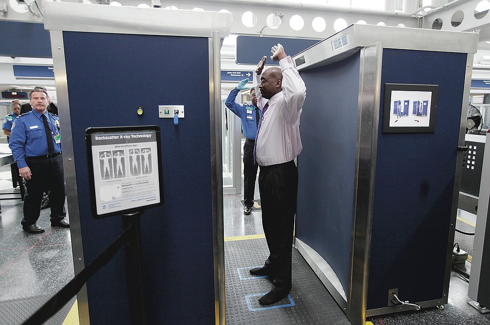 ADVANCE FOR PUBLICATION ON FRIDAY, SEPT. 10, AND THEREAFTER - FILE - In this March 15, 2010 file photo, a volunteer passes through the first full body scanner installed at O'Hare International Airport in Chicago. The technology produces a cartoon-like outline rather than naked images of passengers by using X-rays. (AP Photo/M. Spencer Green, File)