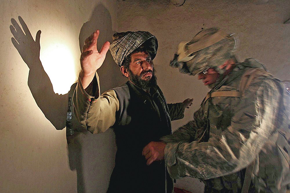 ADVANCE FOR PUBLICATION ON FRIDAY, SEPT. 10, AND THEREAFTER - FILE - In this Monday, April 2, 2007 file photo, a U.S. soldier of B company, 4th Infantry Regiment frisks an afghan man in his house during a search operation in Sinan village in Zabul province, southeastern Afghanistan. (AP Photo/Rafiq Maqbool, File)