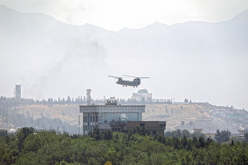 ADVANCE FOR PUBLICATION ON FRIDAY, SEPT. 10, AND THEREAFTER - FILE - In this Sunday, Aug. 15, 2021 file photo, a U.S. Chinook helicopter flies over the U.S. embassy in Kabul, Afghanistan. Helicopters landed at the embassy as diplomatic vehicles left the compound amid the Taliban advance on the Afghan capital. (AP Photo/Rahmat Gul, File)