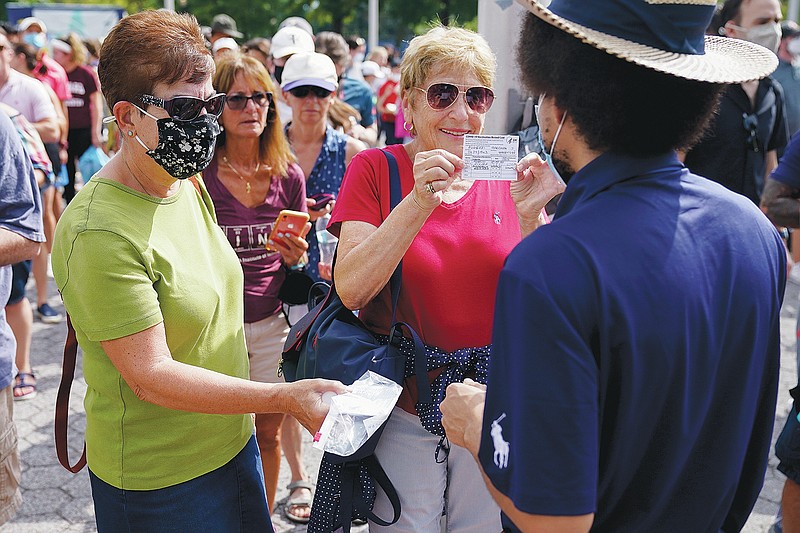 Tennis fans show their proof of vaccination cards for entry to attend the first round of the US Open tennis championships, Monday, Aug. 30, 2021, in New York. (AP Photo/Seth Wenig)