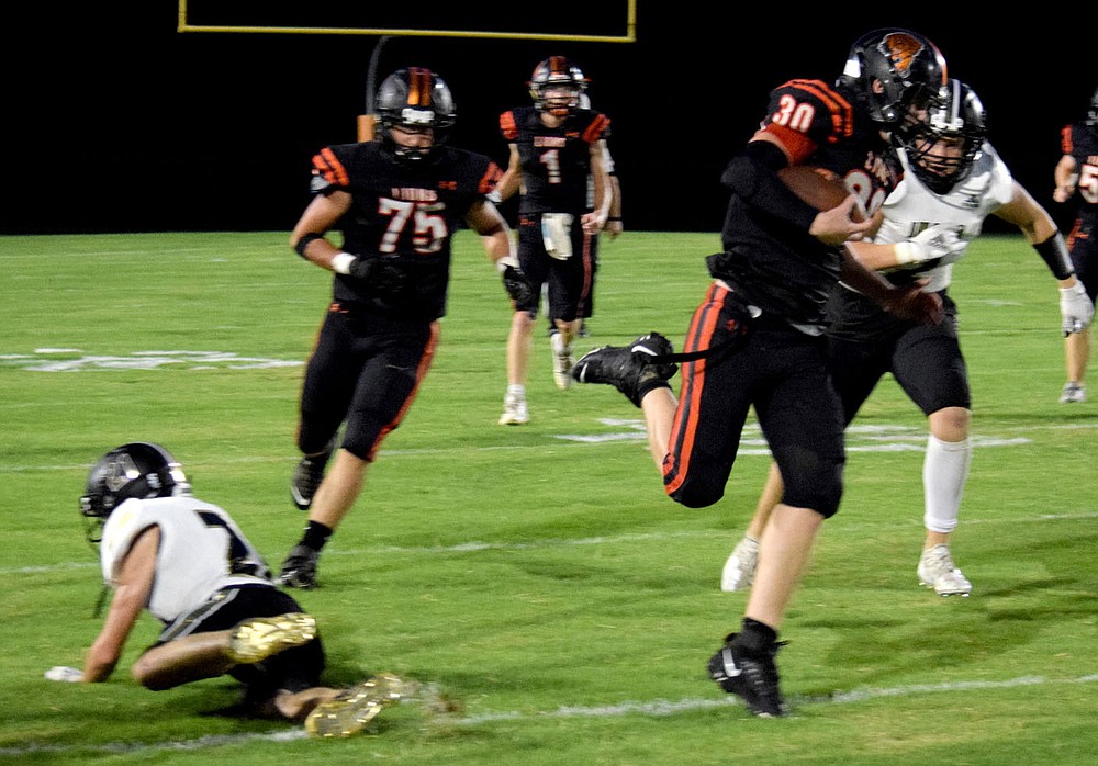 Westside Eagle Observer/MIKE ECKELS
Kyler Austin (Gravette 30) literally jumps out of a tackle (lower left) and continues to gain yardage during the Friday night football contest between the Gravette Lions and the Inola, Oklahoma Longhorns at Lion Stadium in Gravette. Austin managed another 10 yards before being tackled by another Longhorn.