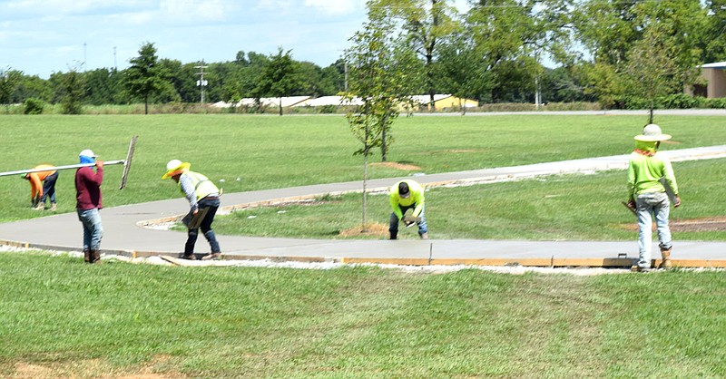 Westside Eagle Observer/MIKE ECKELS
Workers put the finishing touches on the track that ties into the Veterans Park Walking Trail Aug. 31 in Decatur. The Decatur City Council decided that the trail system would look better if the old asphalt surface was replaced with concrete to give the trail a more constant look.