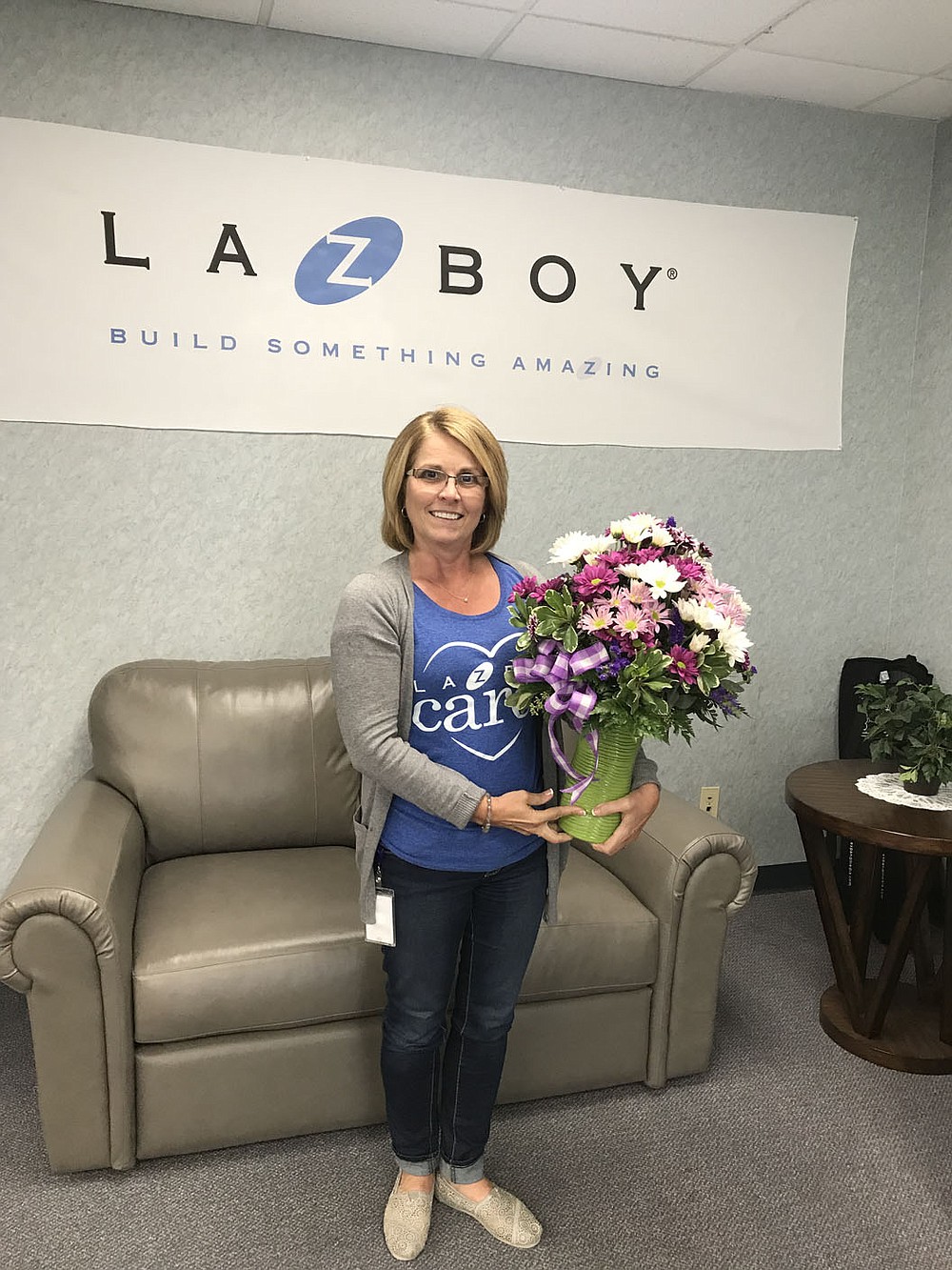 Photo submitted Audra Farrell poses with flowers in front of the La-Z-Boy sign on her last day of work at the furniture magnet. Farrell, who was chosen to receive an award during the Outstanding Civic Leadership Event said she enjoyed her time at La-Z-Boy and will miss the friendships she has developed there.