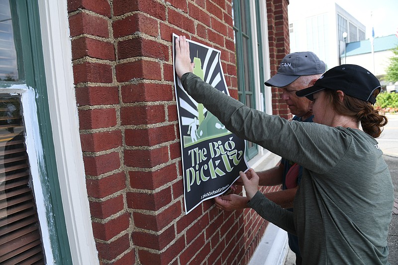 Kate Tully, front, and David Tappe put up posters for The Big Pickle pickleball festival at Transportation Depot. The festival starts today. - Photo by Tanner Newton of The Sentinel-Record