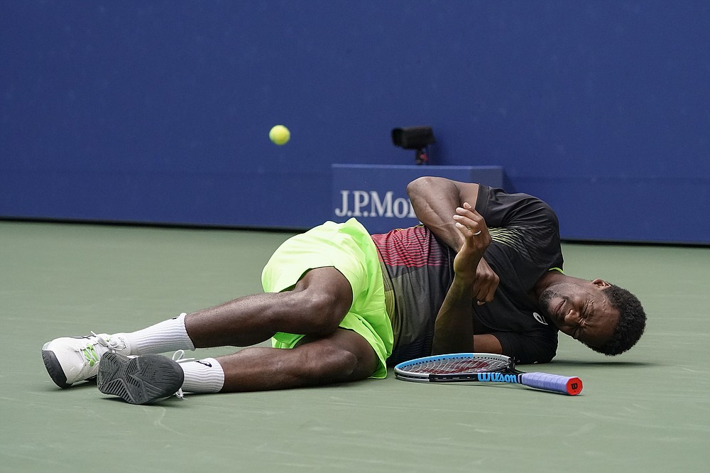 Francouz Gael Monfils reaguje poté, co upadl před kurt, zatímco pronásledoval střelu z USA Steva Johnsona, během druhého kola US Open, čtvrtek 2. září 2021 v New Yorku.  (AP Photo/John Minchillo)