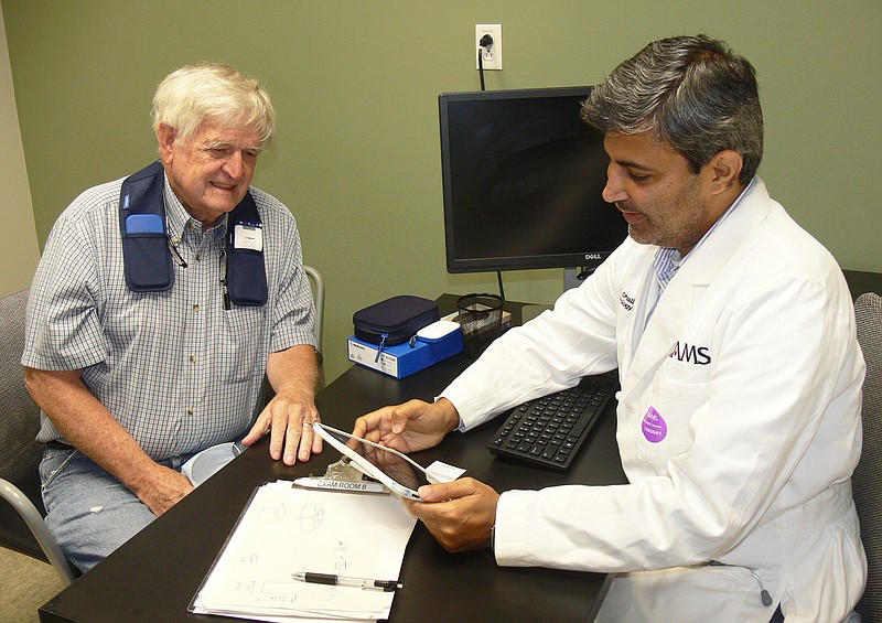 Jerry Butler (left) describes what he's feeling as Dr. Rohit Dhall (right) fine tunes impulses produced by a deep brain stimulation electronic tremor-control device implanted in Butler's brain at the UAMS Medical Center in June. Dhall is a professor of neurology and the director of Neurodegenerative Disorders at the University of Arkanas for Medical Sciences. (Special to the Democrat-Gazette/Jerry Butler)