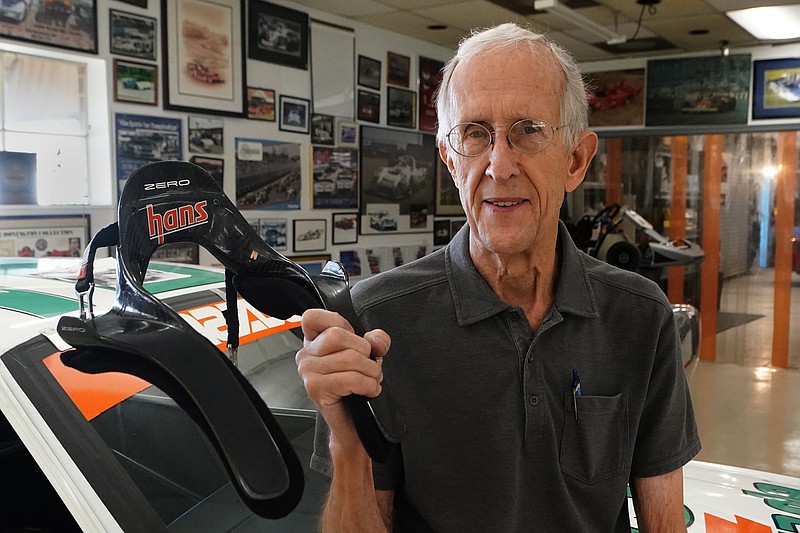 Jim Downing poses with the HANS (Head And Neck Support) device he co-invented with his brother-in-law, Wednesday, Sept. 1, 2021, at his race shop in Atlanta. The device keeps a driver's head from violently snapping forward in an accident and has been credited with saving numerous lives in its two decades of use. (AP Photo/John Bazemore)