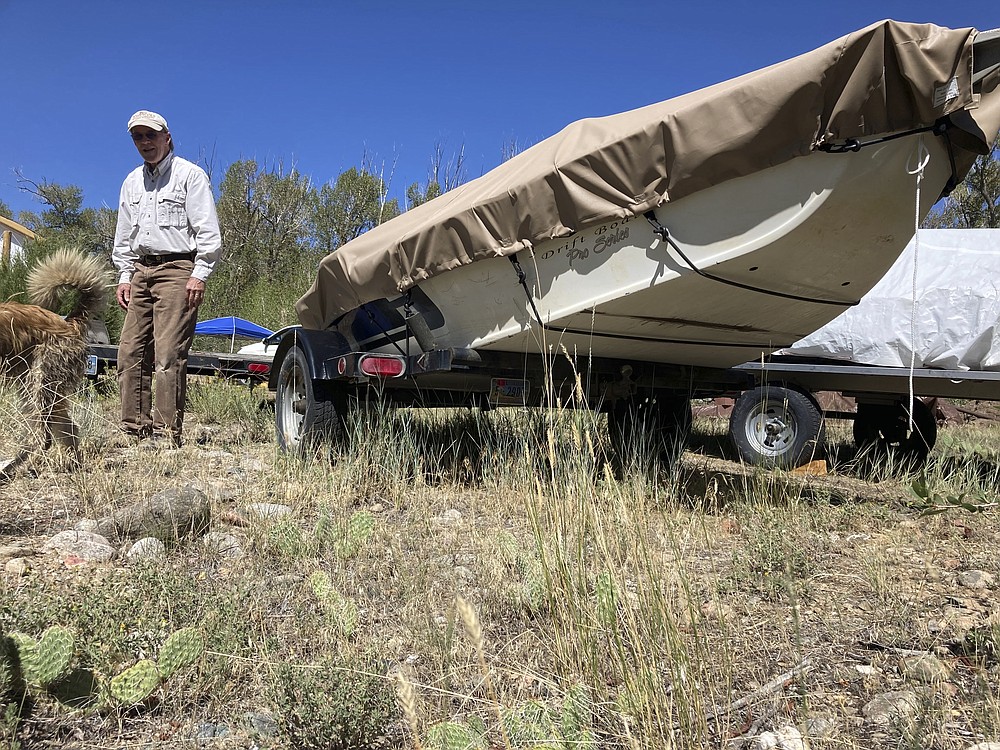 Tom Wiersema, who has been trout fishing on the upper North Platte River in Wyoming since the 1970s, stand by his drift boat near Encampment,Wyoming on Tuesday,Aug. 24, 2021. Low water caused Wiersema to stop fishing by boat on a long stretch of the river earlier than usual this year, lest he have to drag his boat over rocks. The upper North Platte is one of several renowned trout streams affected by climate change, which has brought both abnormally dry, and sometimes unusually wet, conditions to the western U.S. (AP Photo/Mead Gruver)