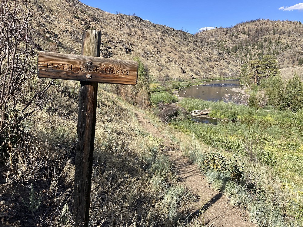 A trail sign burned by a recent wildfire stands near the North Platte River in southern Wyoming, on Tuesday,Aug. 24, 2021.The upper North Platte is one of several renowned trout streams affected by climate change, which has brought both abnormally dry, and sometimes unusually wet, conditions to the western U.S. (AP Photo/Mead Gruver)