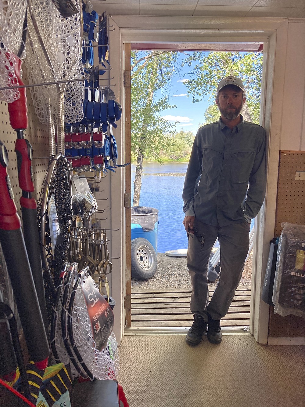 Phil McGrath, owner of Hack's Tackle and Outfitters, stands in a doorway at his store alongside the North Platte River in Saratoga, Wyoming, on Tuesday,Aug. 24, 2021. The upper North Platte is one of several renowned trout streams affected by climate change, which has brought both abnormally dry, and sometimes unusually wet, conditions to the western U.S. (AP Photo/Mead Gruver)