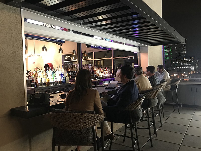 Patrons sat at the outdoor bar at Agasi 7 on a pleasant November 2018 evening. The rooftop bar, which was expected to reopen over Labor Day weekend after months of covid-19-caused closure, won't reopen before Sept. 17. (Democrat-Gazette file photo)