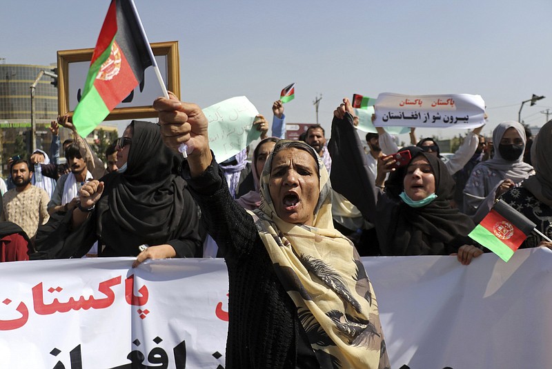 Afghan women shout slogans and wave Afghan national flags during an anti-Pakistan demonstration, near the Pakistan embassy in Kabul, Afghanistan, Tuesday, Sept. 7, 2021. Sign in Persian at right reads, &quot;Pakistan Pakistan Get out from Afghanistan.&quot; (AP Photo/Wali Sabawoon)