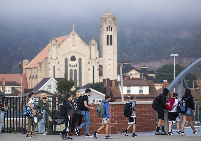 Students arrive at Ambridge Area Senior High School on the first day of Pennsylvania's mask mandate for K-12 schools and day care centers on Tuesday, Sept. 7, 2021, in Ambridge, Pa. St. Mary's Coptic Orthodox Church can be seen in the background. (Andrew Rush /Pittsburgh Post-Gazette via AP)