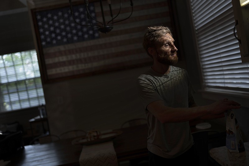 Brad Snyder prepares tea on Aug. 4 for his wife in their kitchen decorated with a flag handcrafted by Brooklyn firefighters using recycled firehose, in Princeton, N.J. Losing his sight, he says, seems to matter more to other people. - Photo by Emilio Morenatti of The Associated Press