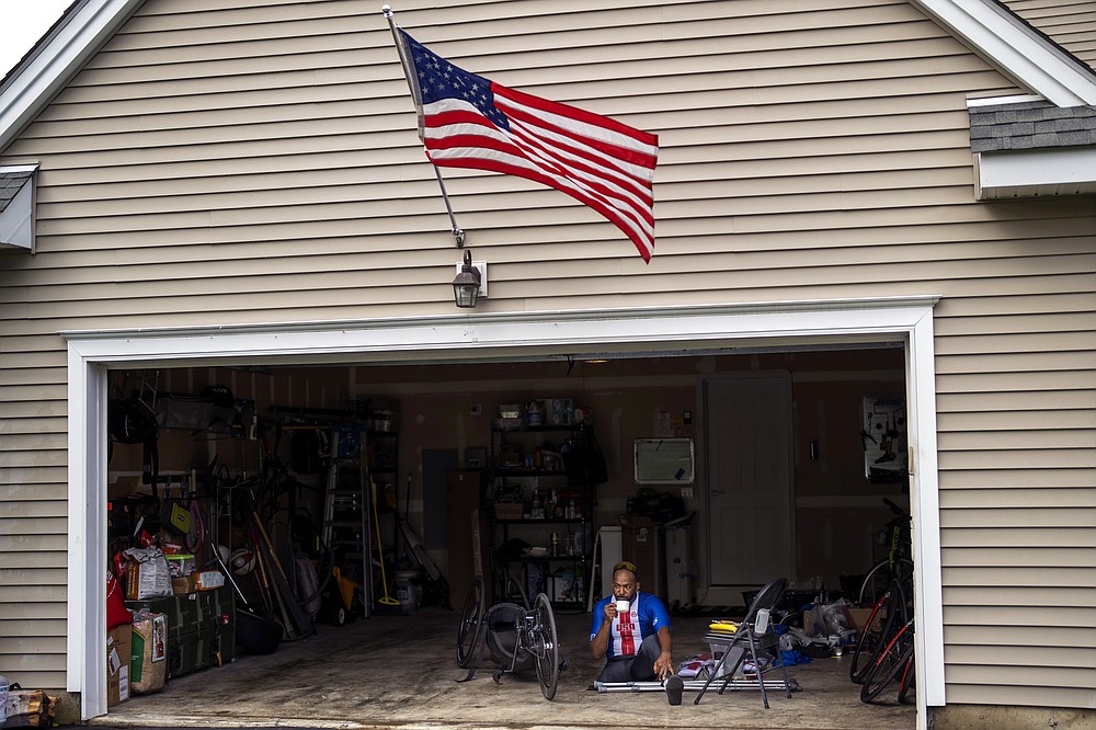 Freddie De Los Santos sits in his garage before his daily training in Hopewell Junction, N.Y., on Wednesday, Aug. 19, 2021. De Los Santos, 51, who grew up in a rough New York City neighborhood at the height of the crack cocaine epidemic, has created an idyllic small-town life north of the city. (AP Photo/Emilio Morenatti)