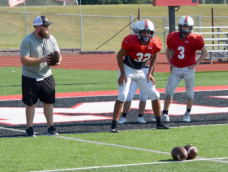 Al Gaspeny/Special to McDonald County Press
McDonald County running back Jared Mora (32) gets set as assistant coach Daniel Sumler and running back Cory Eastburn (3) watch during Tuesday's workout at Mustang Stadium.