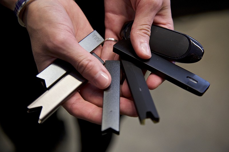 FILE - In this April 16, 2019 file photo, a researcher holds vape pens in a laboratory in Portland, Ore. On Thursday, Sept. 9, 2021, U.S. health officials delayed a high-stakes decision on whether to permit best selling vaping brand Juul to stay on the market, while ordering thousands of other electronic cigarettes off store shelves. (AP Photo/Craig Mitchelldyer, File)