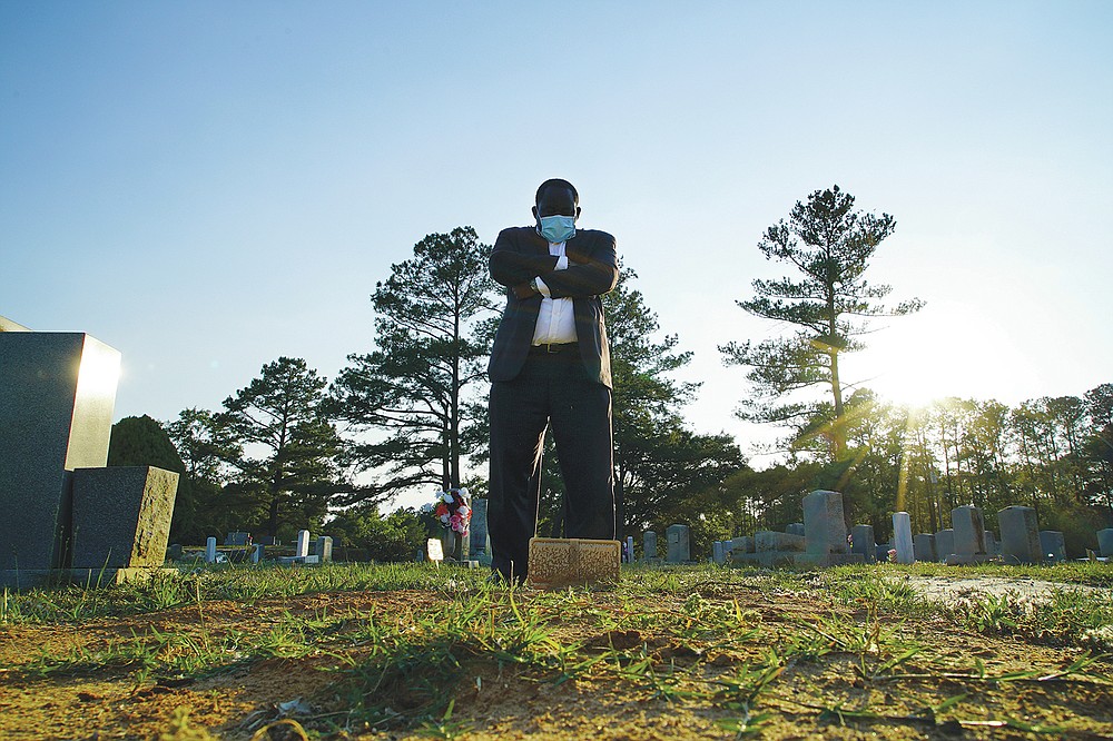 Mortician Shawn Troy stands at the grave of his father, William Penn Troy Sr., at Hillcrest Cemetery outside Mullins, S.C., on Sunday, May 23, 2021. The elder Troy, who developed the cemetery, died of COVID-19 in August 2020, one of many Black funeral directors to succumb during the pandemic. &#x201c;I don&#x2019;t think I&#x2019;ll ever get over it,&#x201d; he said. &#x201c;But I&#x2019;ll get through it.&#x201d; (AP Photo/Allen G. Breed)