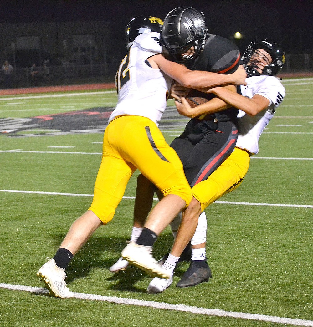 ANNETTE BEARD PEA RIDGE TIMES/Prairie Grove Tiger defenders tackle Gavin Dixon (No. 15), the Blackhawk quarterback on Friday, Sept. 10 in Blackhawk Stadium. Prairie Grove won the nonconference contest 41-28. Next season the teams will likely become league foes once again with Prairie Grove moving up to the 5A Classification.