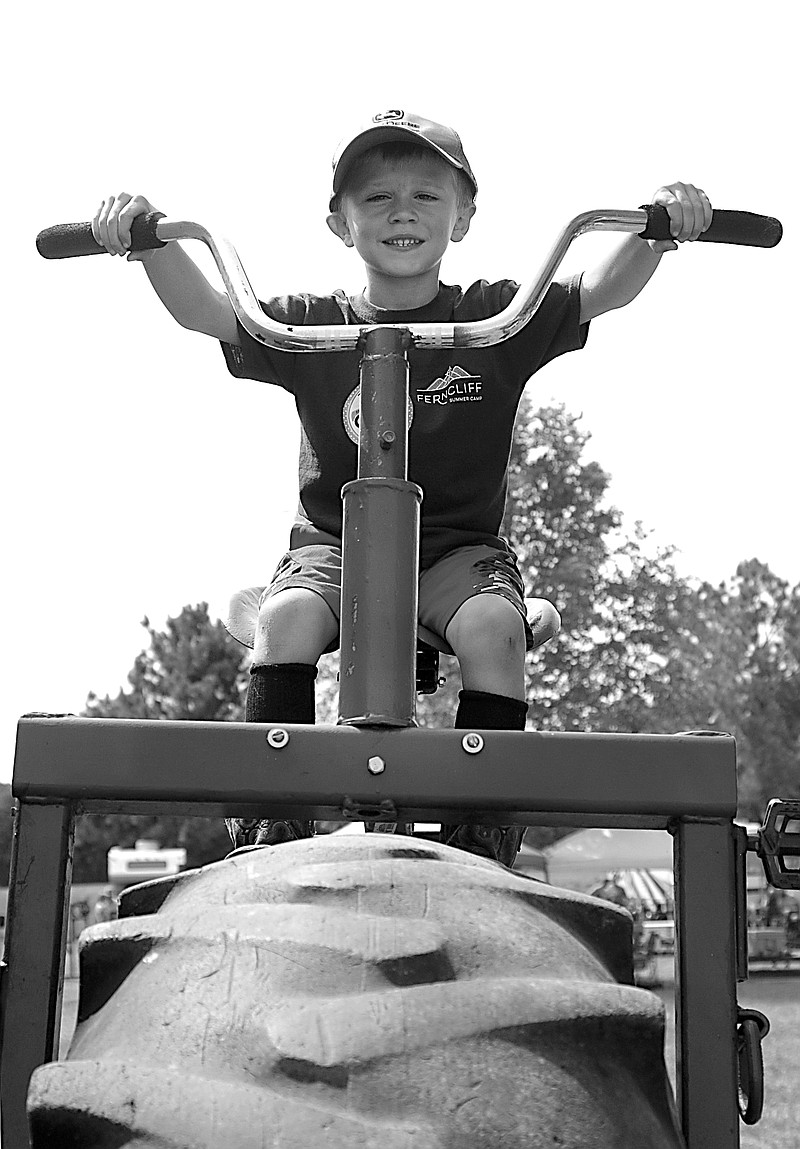 Westside Eagle Observer/RANDY MOLL
Paxton Smith, 5, sits atop a tractor-size tricycle at the Tired Iron of the Ozarks fall show in Gentry on Saturday, Sept. 11, 2021.