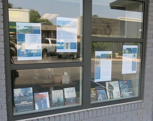 Westside Eagle Observer/SUSAN HOLLAND
The front windows at the Gravette Public Library hold a display of posters developed by the 9/11 Memorial and Museum to explain the events of the Sept. 11, 2001, terrorist attack to youngsters who were not yet born at the time of the incident. Also on display are books from the library's collection relating to the attack.