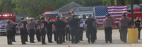 Westside Eagle Observer/SUSAN HOLLAND
Members of the Gravette fire department and police department, joined by members of the Maysville fire department and area first responders, stand at attention and salute as lights on their emergency vehicles flash following the reading of the names of all 343 firefighters and paramedics who lost their lives in the Sept. 11, 2001 World Trade Center attack.