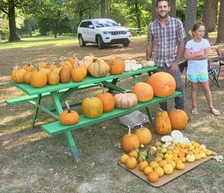 Westside Eagle Observer/SUSAN HOLLAND
Charles Conway poses with his daughter Alexis Johnson Conway, 9, and several samples from this year's pumpkin crop at the Gravette farmers' market Saturday morning, Sept. 11. With the arrival of cooler weather and the fall season only a couple of weeks away, Conway was selling several pumpkins for autumn decorating and baking of tasty treats.
