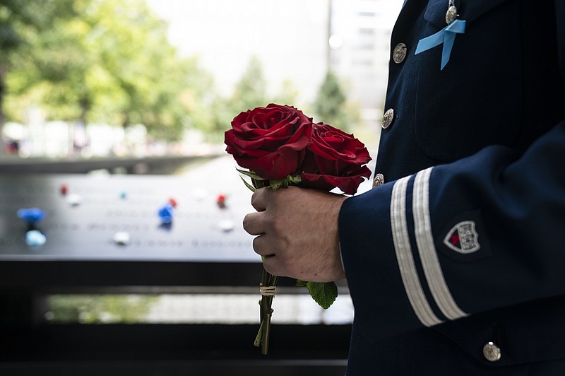 A mourner brings roses to the north pool after the conclusion of ceremonies to commemorate the 20th anniversary of the Sept. 11 terrorist attacks, Saturday, Sept. 11, 2021, at the National September 11 Memorial &amp; Museum in New York. (AP Photo/John Minchillo)