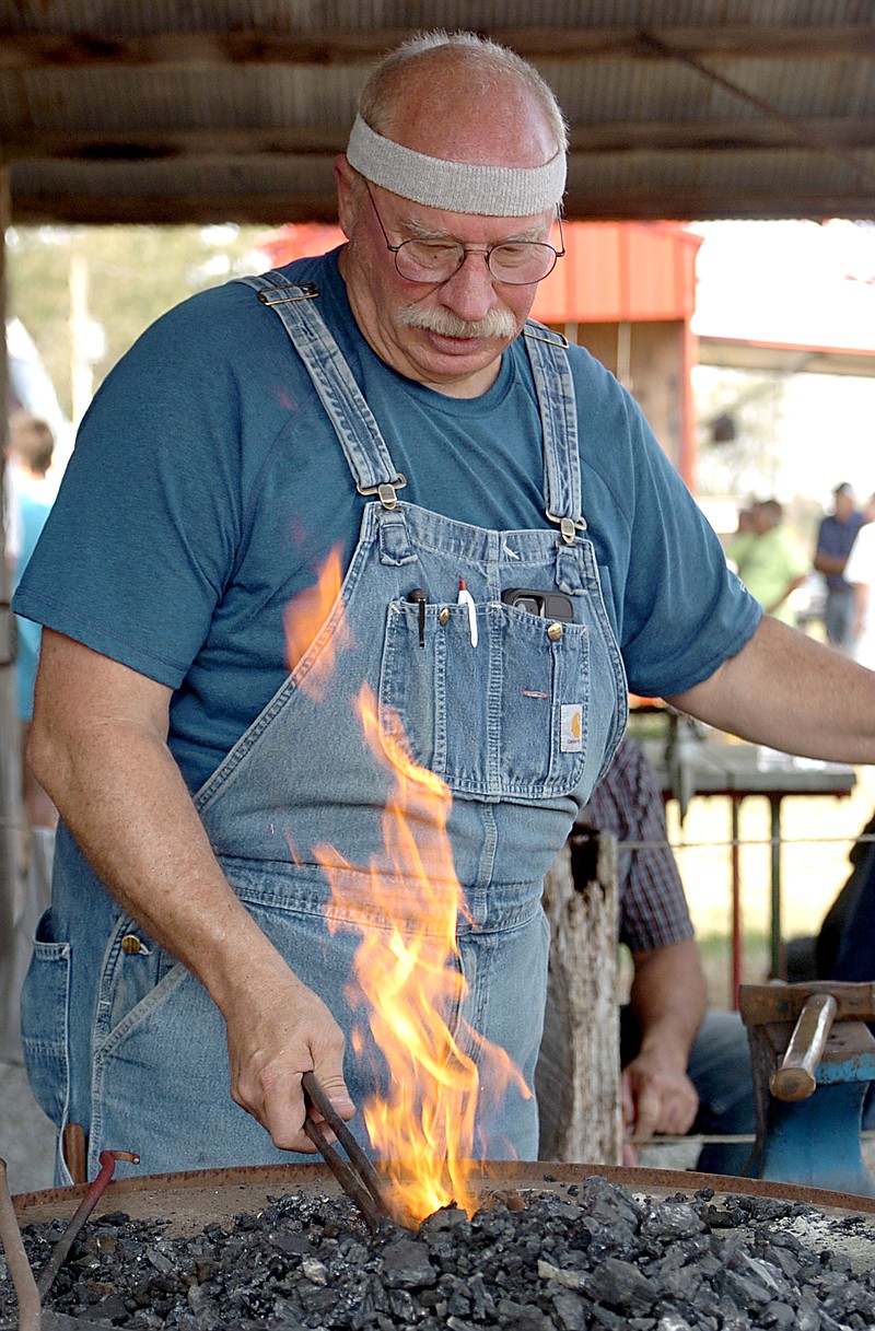 Westside Eagle Observer/RANDY MOLL
Lin Rhea, of Prattsville, a member of the American Bladesmith Association, heats up a piece of iron as he demonstrates the art to a crowd of visitors Saturday at the Tired Iron of the Ozarks fall show in Gentry. Members of the American Bladesmith Association and the Blacksmith Organization of Arkansas were at the annual show and talking with spectators on Saturday.