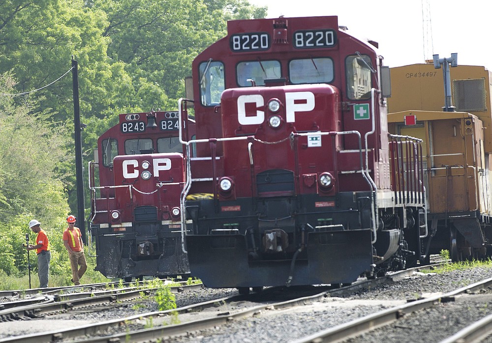 FILE - In this May 23, 2012, file photo, surveyors work next to Canadian Pacific Rail trains which are parked on the train tracks in Toronto. A planned shareholder vote on Canadian National's $33.6 billion offer has been delayed, Wednesday, Sept. 1, 2021, after regulators rejected a key part of the plan, so now Kansas City Southern can consider all of its options, including a competing $31 billion offer from Canadian Pacific Railway. (Nathan Denette/The Canadian Press via AP, File)